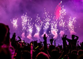 Vibrant EDM concert scene with fireworks, smoke, and enthusiastic crowd enjoying the music.