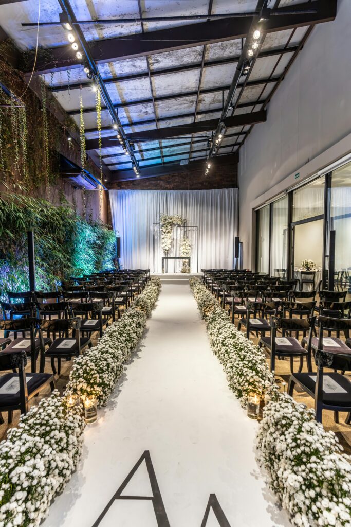 Beautifully decorated indoor wedding aisle with floral arrangements and seating