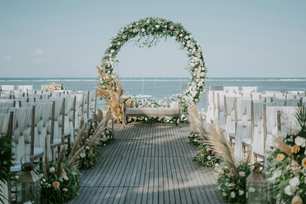 Beautiful beachside wedding setup with elegant floral arch and ocean backdrop.