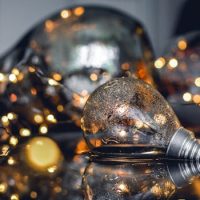 Close-up of wet light bulbs and fairy lights reflecting on a surface.