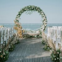 Beautiful beachside wedding setup with elegant floral arch and ocean backdrop.