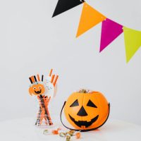 Bright Halloween setup with carved pumpkin, candy, and colorful bunting.